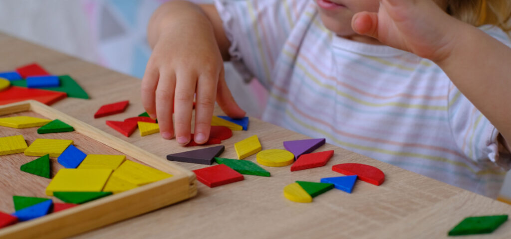 young child playing with wooden block shapes of different colors