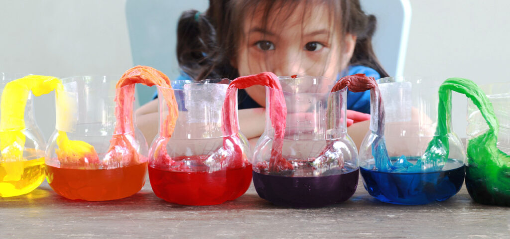 Child using multisensory learning to do a science experiment transferring colored water along paper towels. 